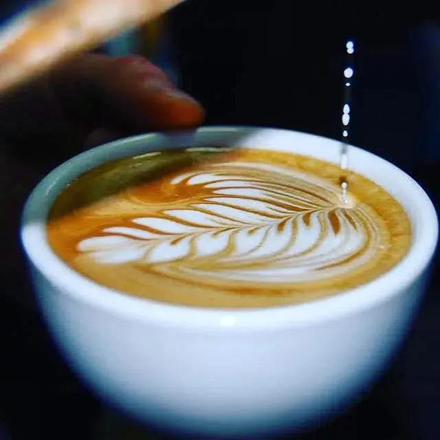 Filiżanka kawy z latte artem w kształcie liścia