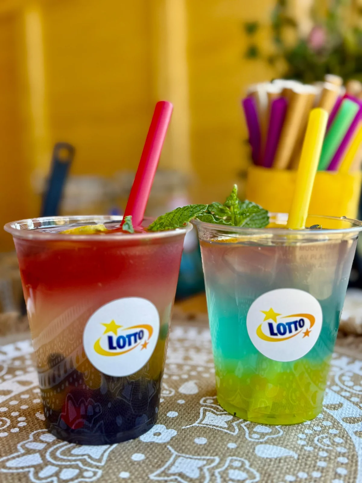 Dwa warstwowe napoje bubble z kolorowymi słomkami, na stoliku w plenerze