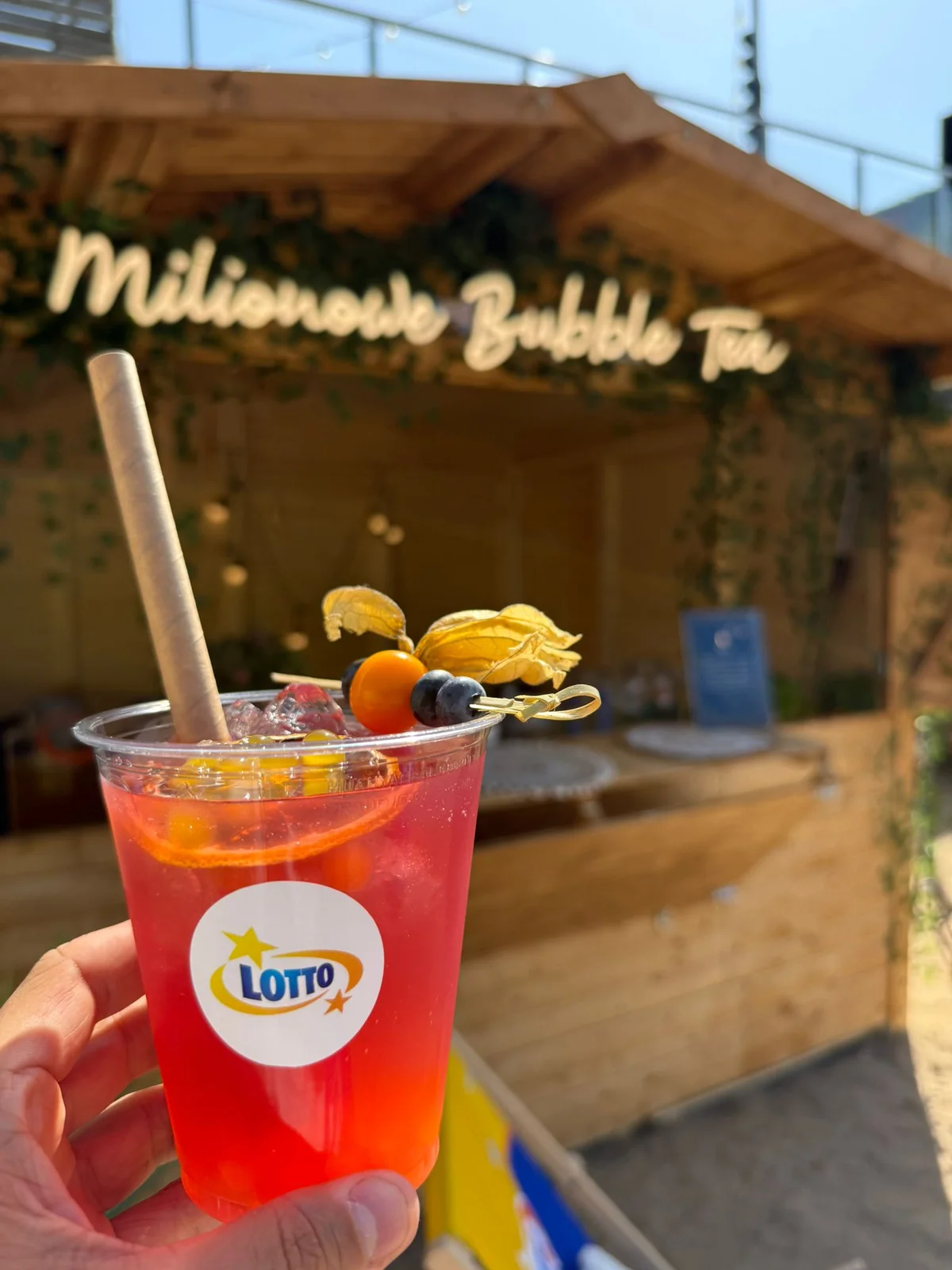 Czerwony napój bubble z owocami przed drewnianym stoiskiem bubble tea