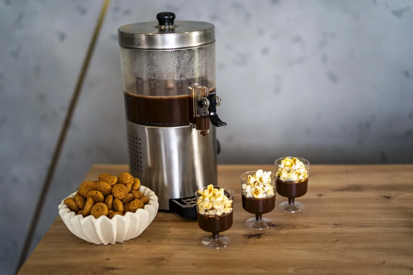 Dyspenser z gorącą czekoladą, misa amaretti i trzy kieliszki czekolady z popcornem