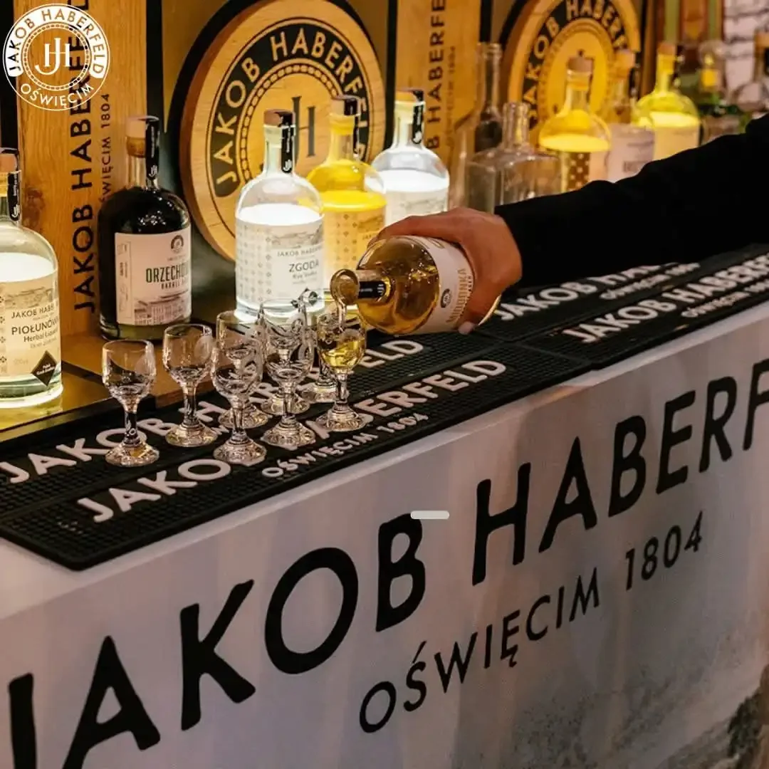 Barman nalewa nalewkę do kieliszków ustawionych na brandowanym barze