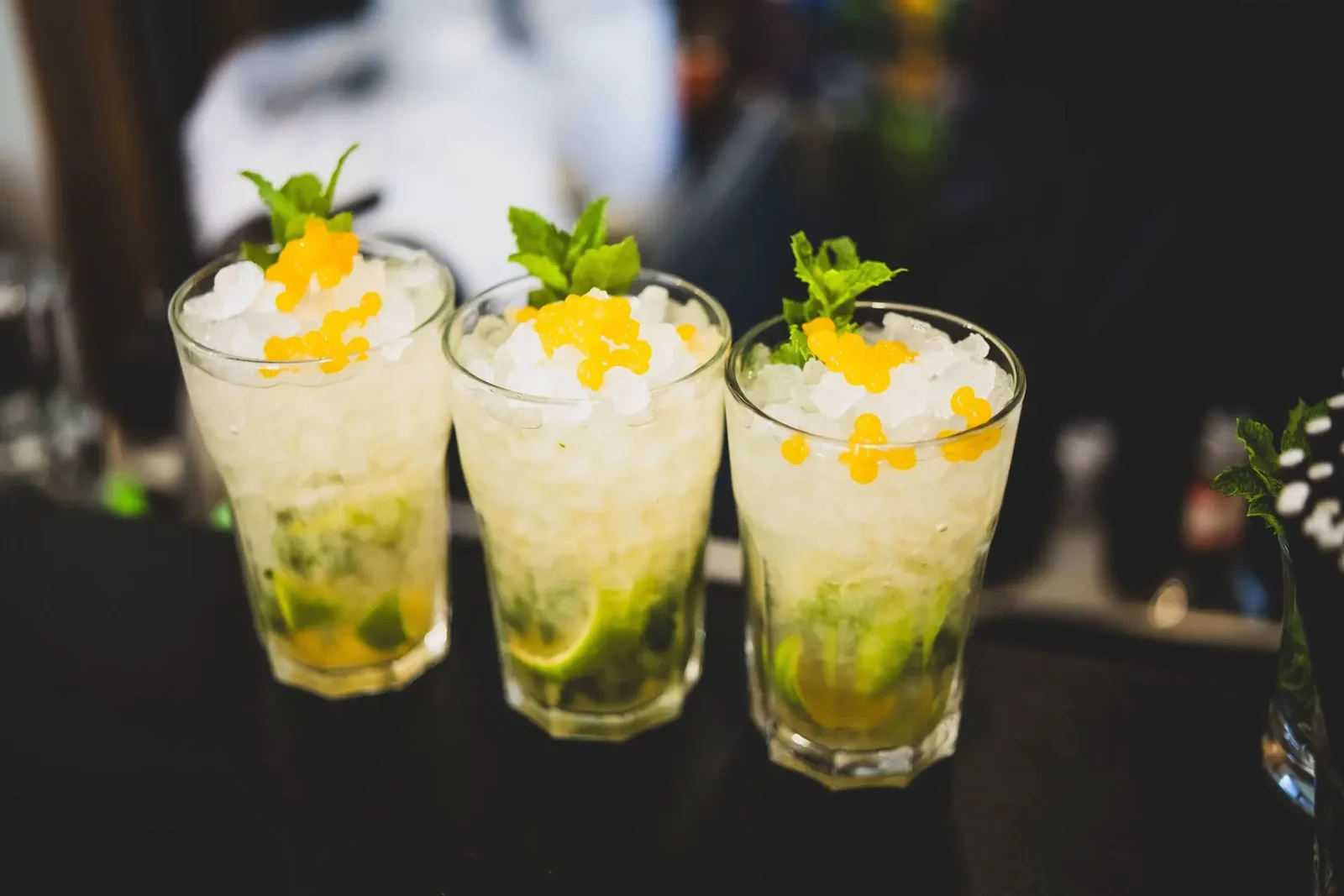 Trzy szklanki mojito z limonką i miętą ustawione w rzędzie na barze