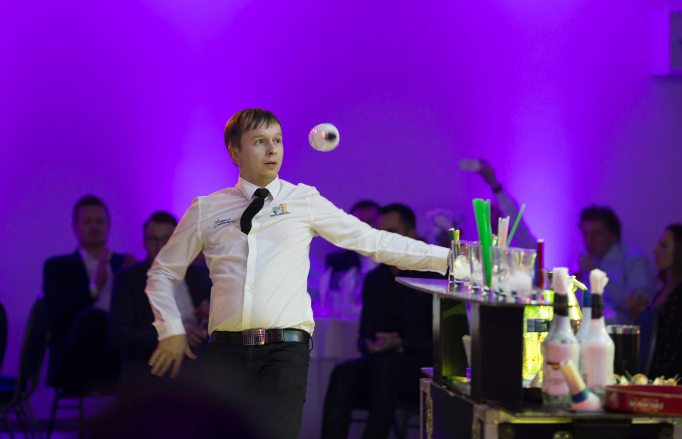 Barman podrzuca shaker podczas występu przed publicznością