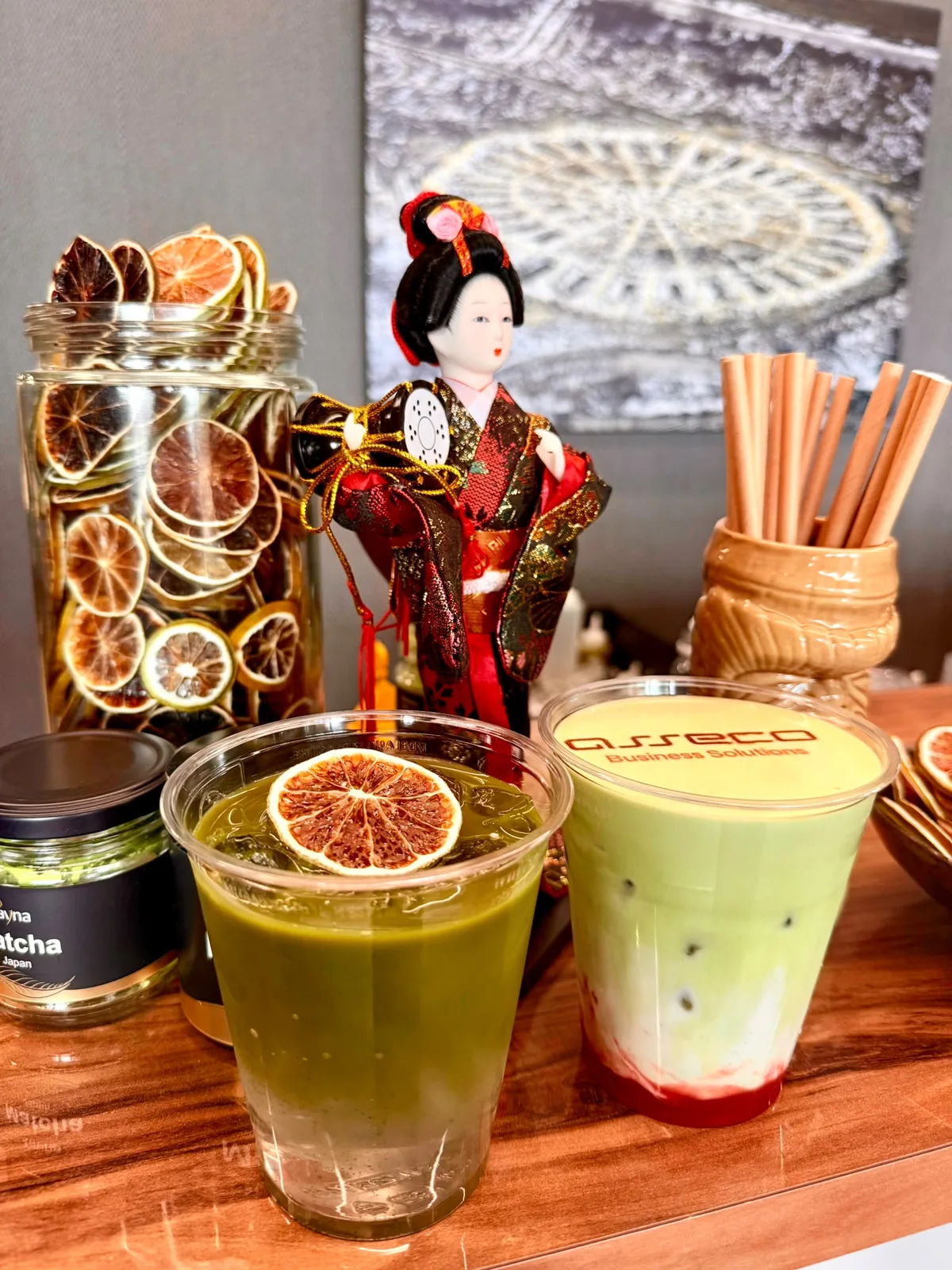 Matcha tonic z plastrem suszonej pomarańczy obok matchy truskawkowej z nadrukiem na piance