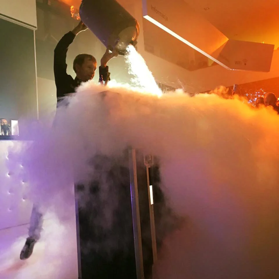 Barman wylewa ciekły azot z kadzi, chmura pary rozświetlona pomarańczowym światłem