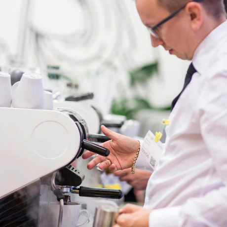Barista obsługujący ekspres do kawy, przygotowujący napój w filiżance