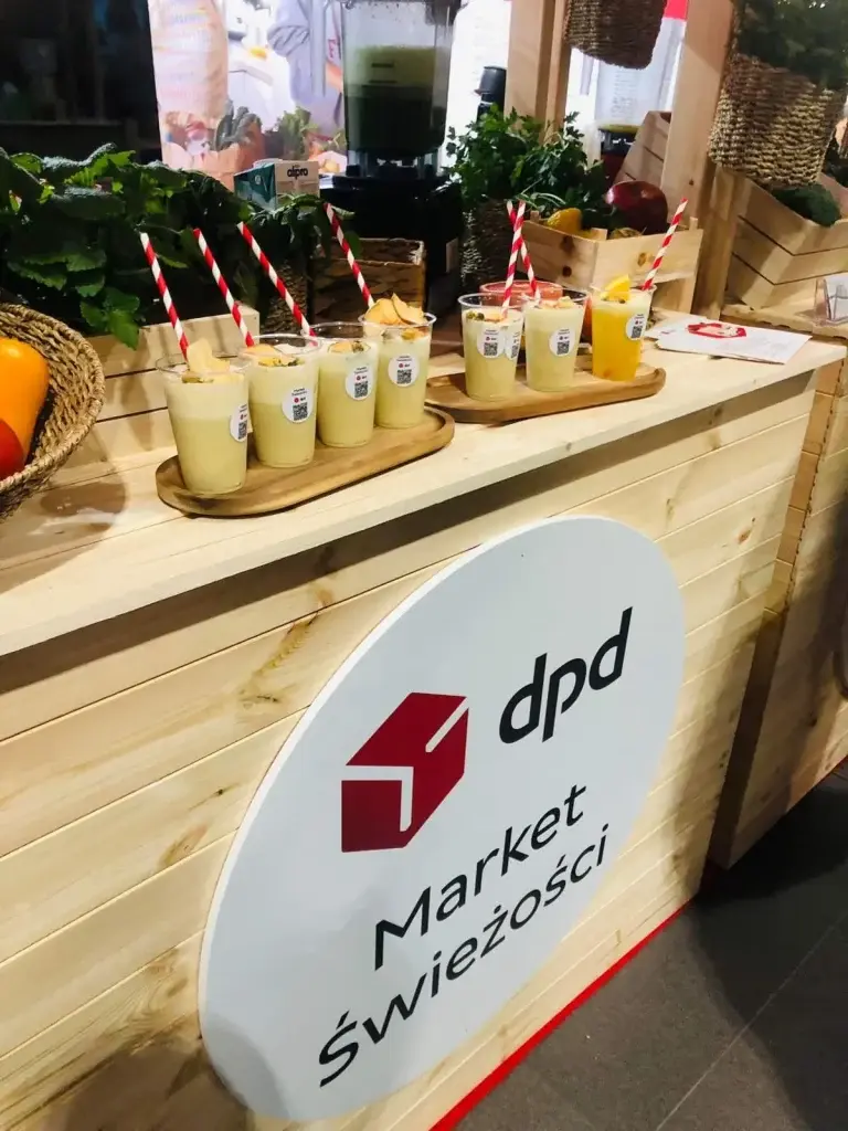 Stoisko DPD Market Świeżości z napojami w przezroczystych kubkach z czerwono-białymi słomkami